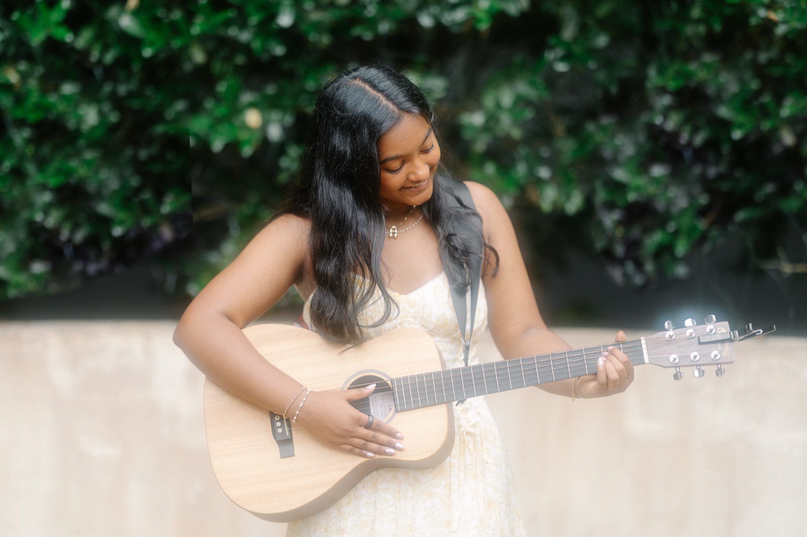 Anya smiling down at her guitar mid-strum