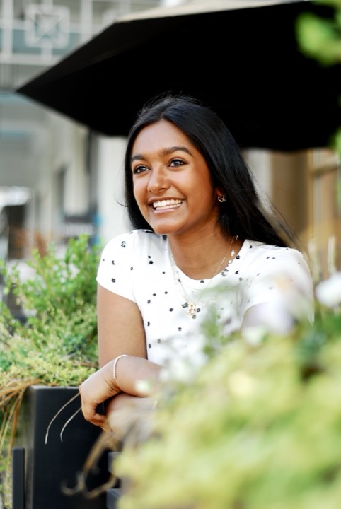 Anya smiling among greenery in golden light