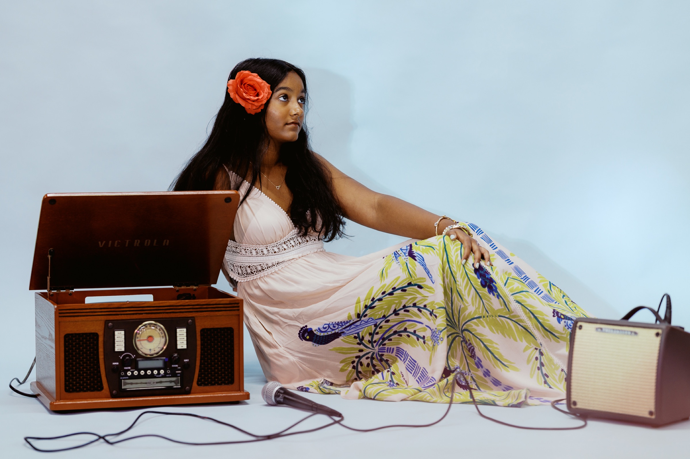 Anya beside the Victrola record player against a powder blue backdrop