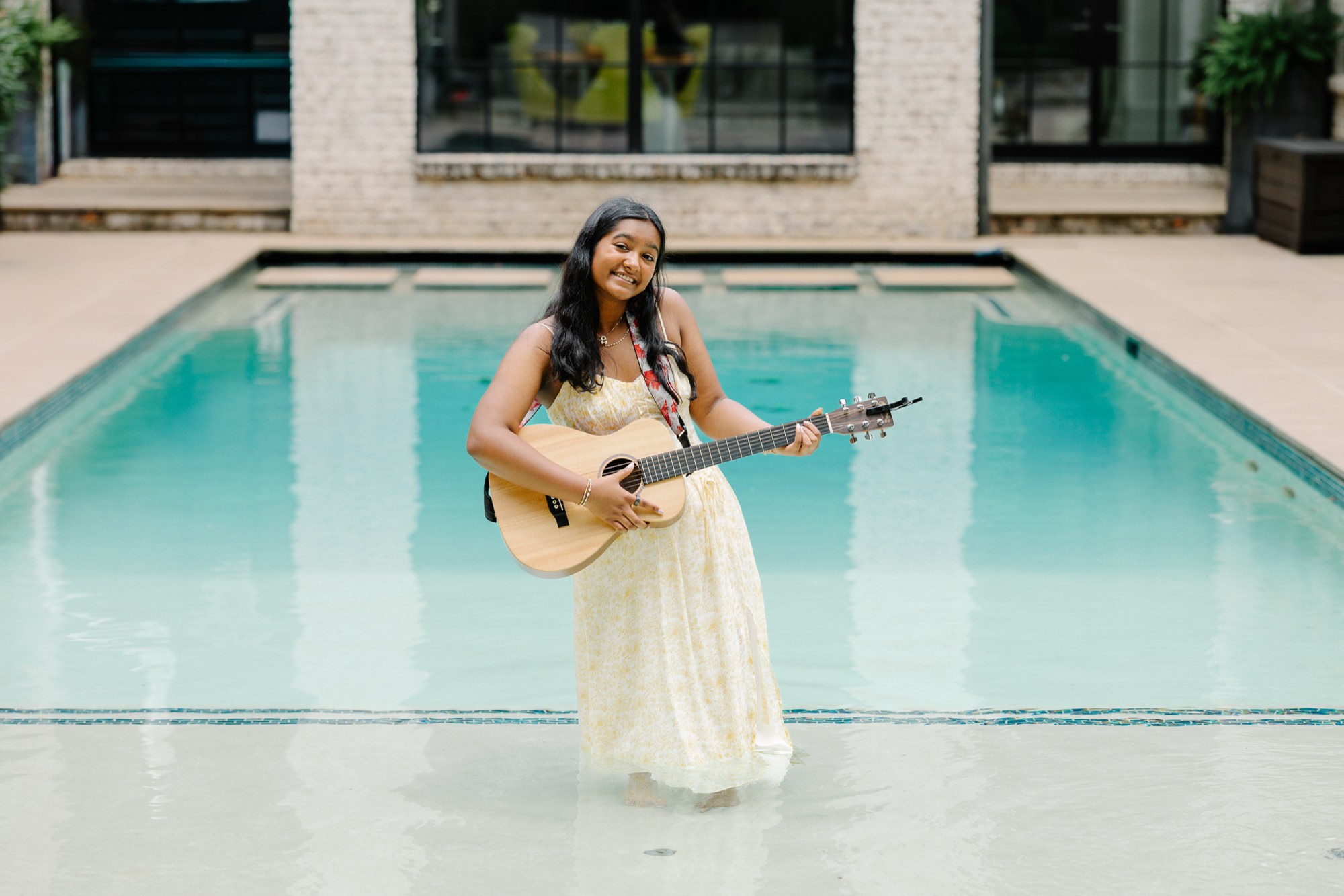 Anya with her guitar, standing in a pool